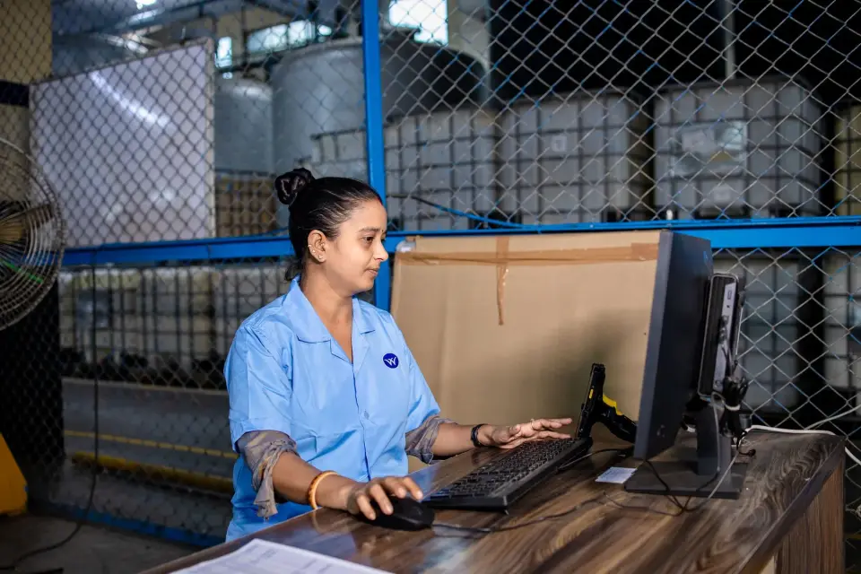 Une employée utilise un poste informatique directement sur le plancher d’une usine